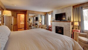 Une chambre d’hôtel dotée d’un grand lit, d’une cheminée, d’une télévision et offrant une vue sur l’extérieur.
