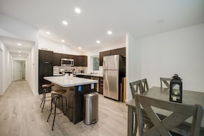 A modern kitchen with a central island, stainless steel appliances, and a dining area with a table and chairs.