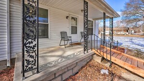 A house with a covered porch, a small outdoor seating area, and a wooden staircase leading to the entrance. - Historical West Mineral Escape w/ Porch! (West Mineral)