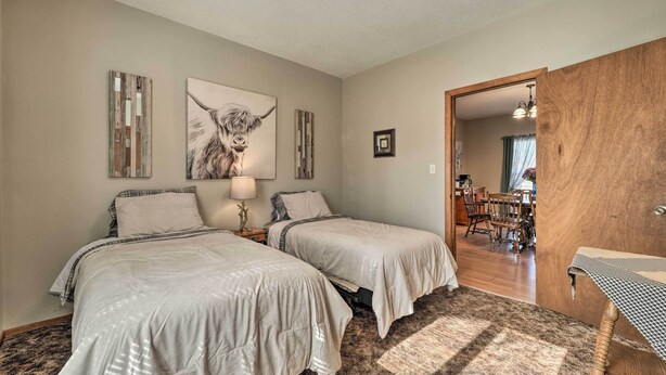 A bedroom with two beds, a wooden door, a dining area, and a hallway. - Historical West Mineral Escape w/ Porch! (West Mineral)