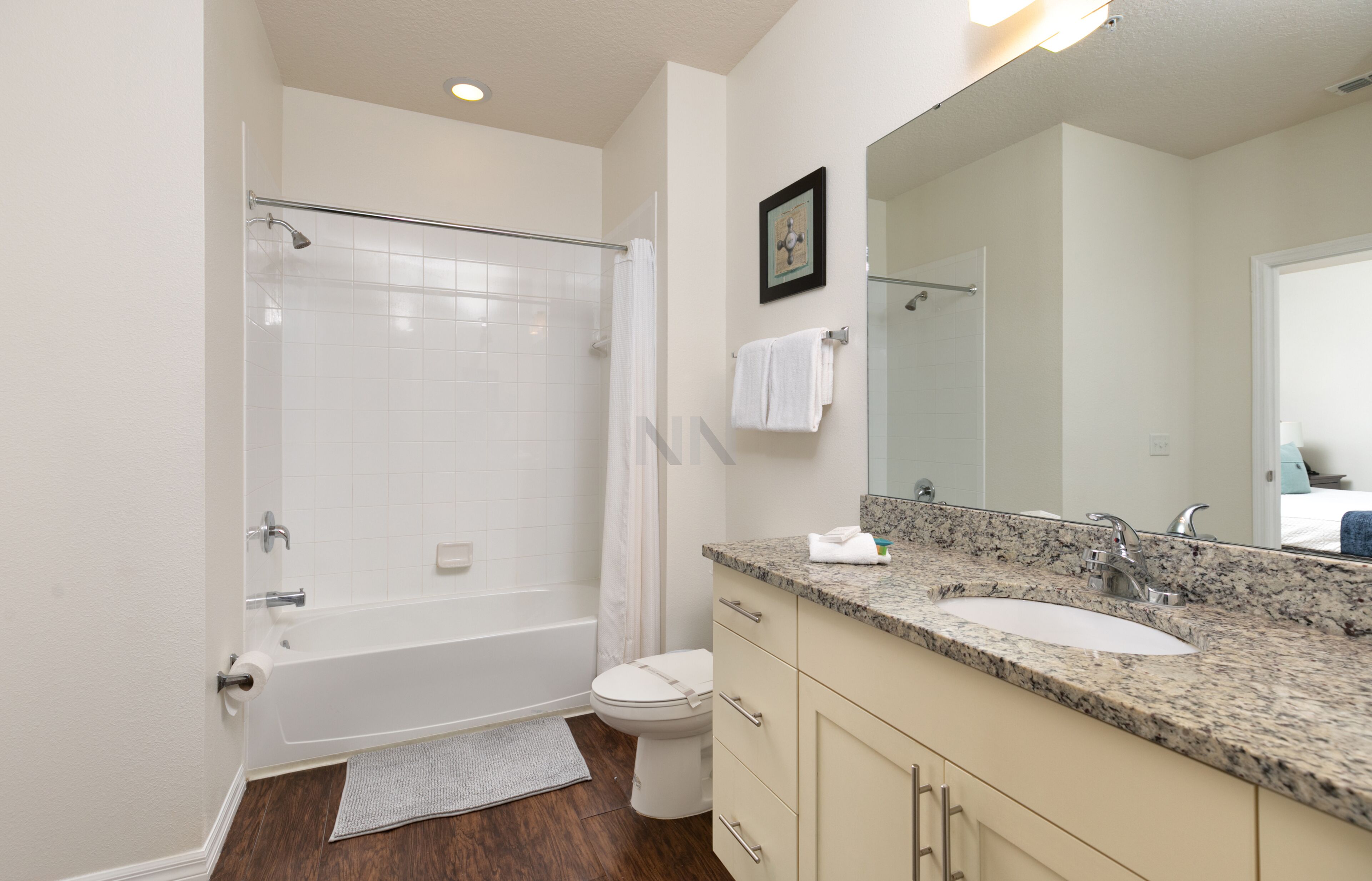 Un bagno moderno con vasca, servizi igienici, lavandino e un ampio specchio.
