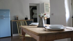 Une cuisine avec une table en bois mise pour le repas, un réfrigérateur bleu et une chaise.