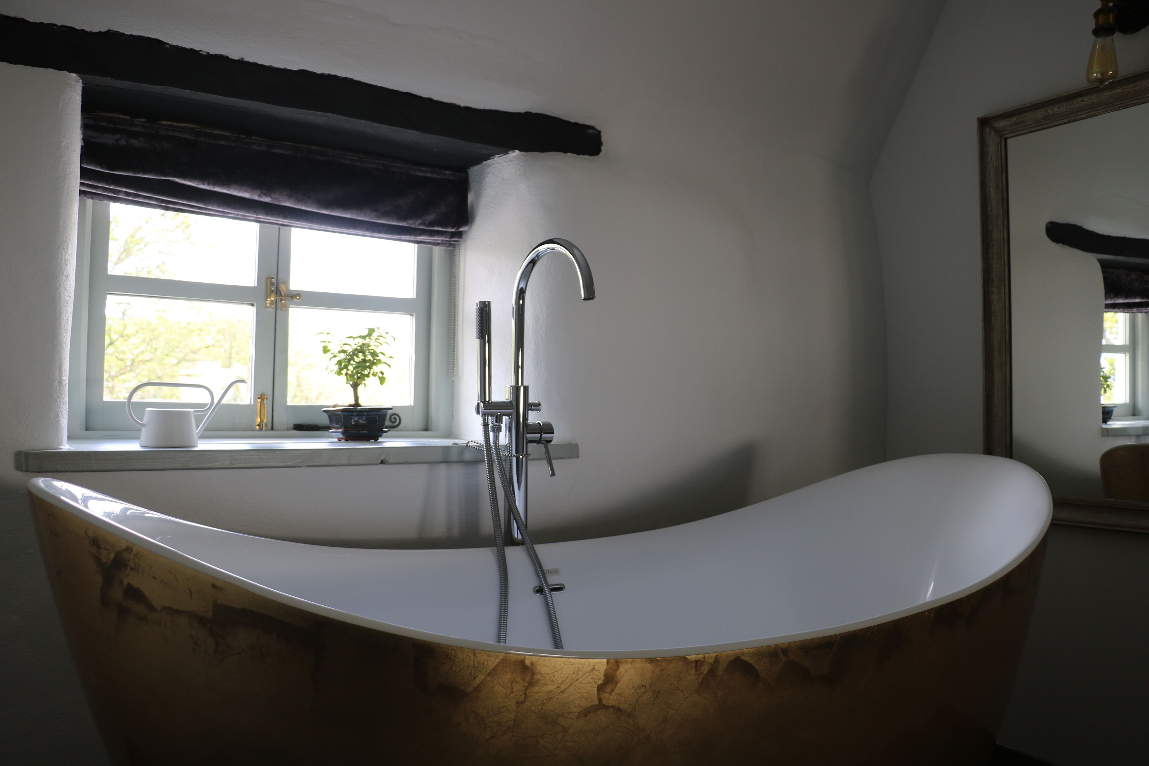 A modern bathroom with a freestanding bathtub, a window with a view, and a mirror.