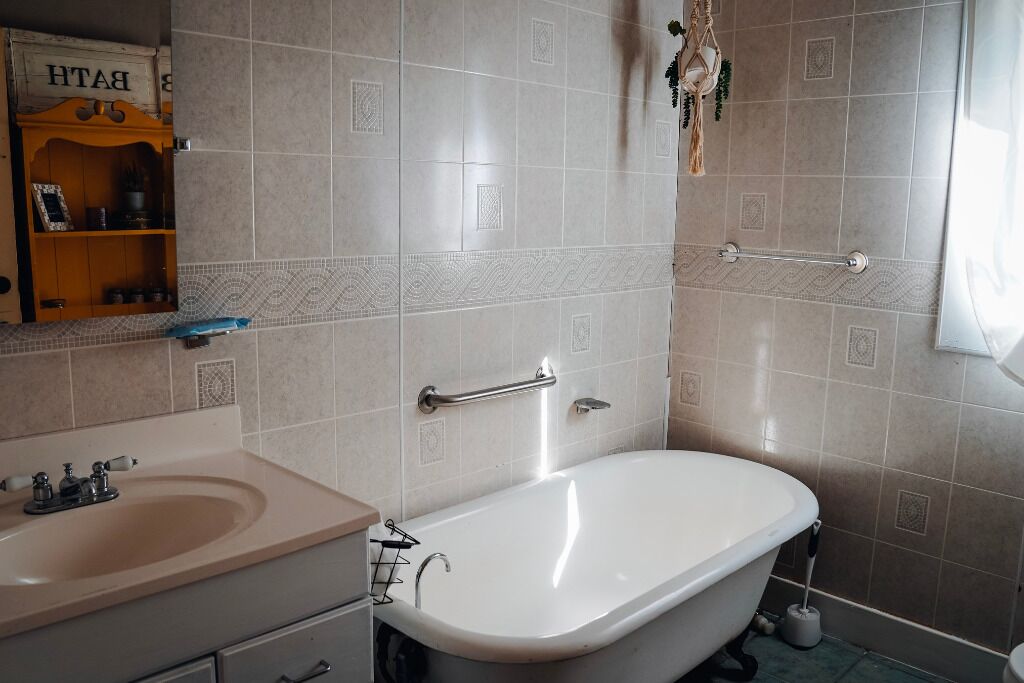 A bathroom with a white bathtub, a beige sink, and a towel rack.