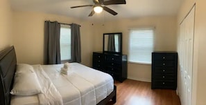 A bedroom with a bed, a ceiling fan, a dresser, and a mirror.