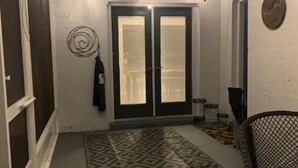A narrow hallway with patterned carpet, a ceiling fan, and a door with frosted glass panels. - Home away from home (Auburndale)