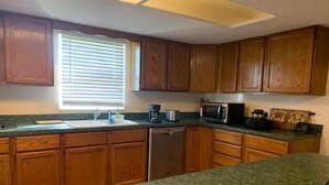 A kitchen with wooden cabinets, a microwave, a coffee maker, and a sink. - Home away from home (Auburndale)