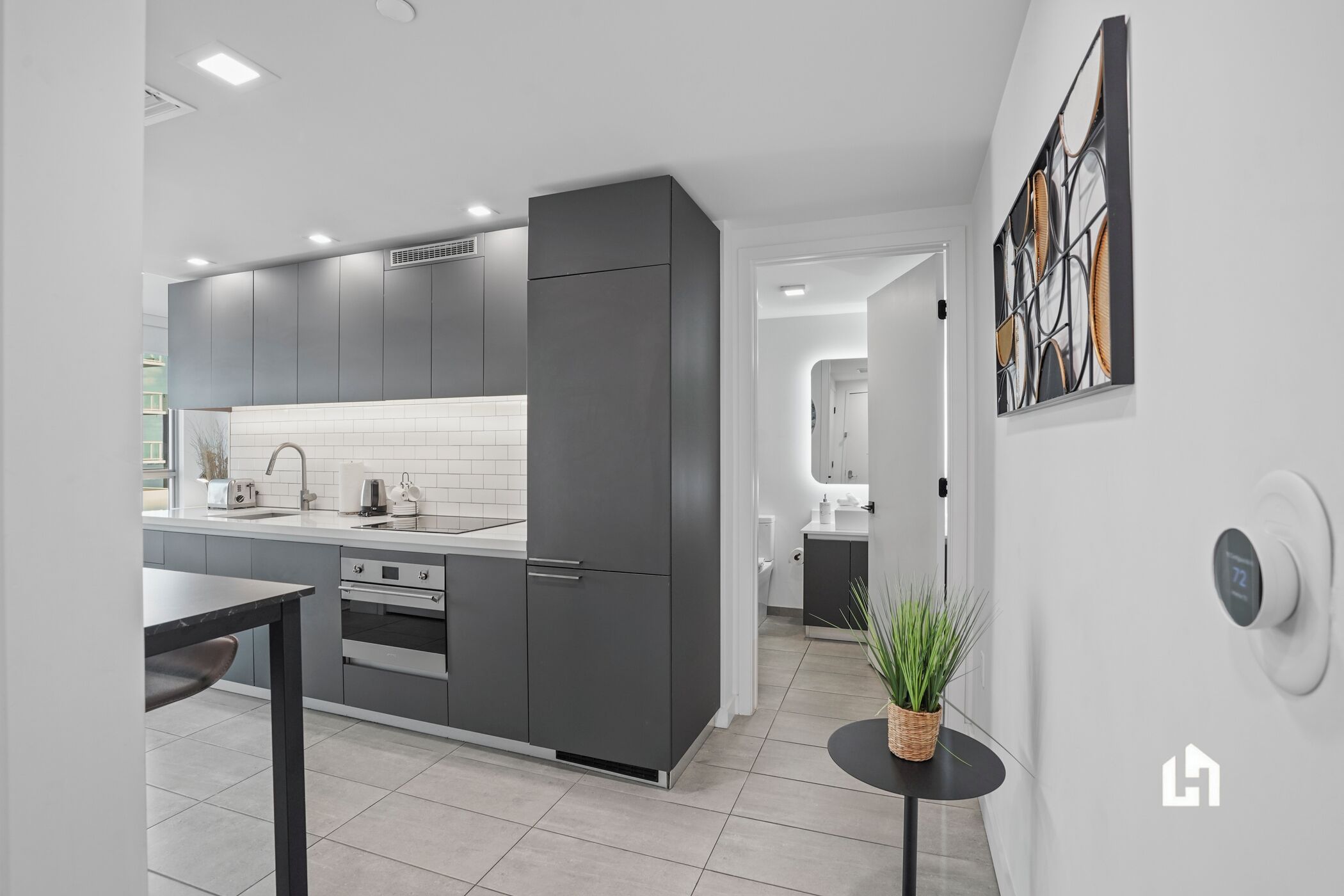 A modern kitchen with grey cabinetry, a white tiled backsplash, and a built-in oven.