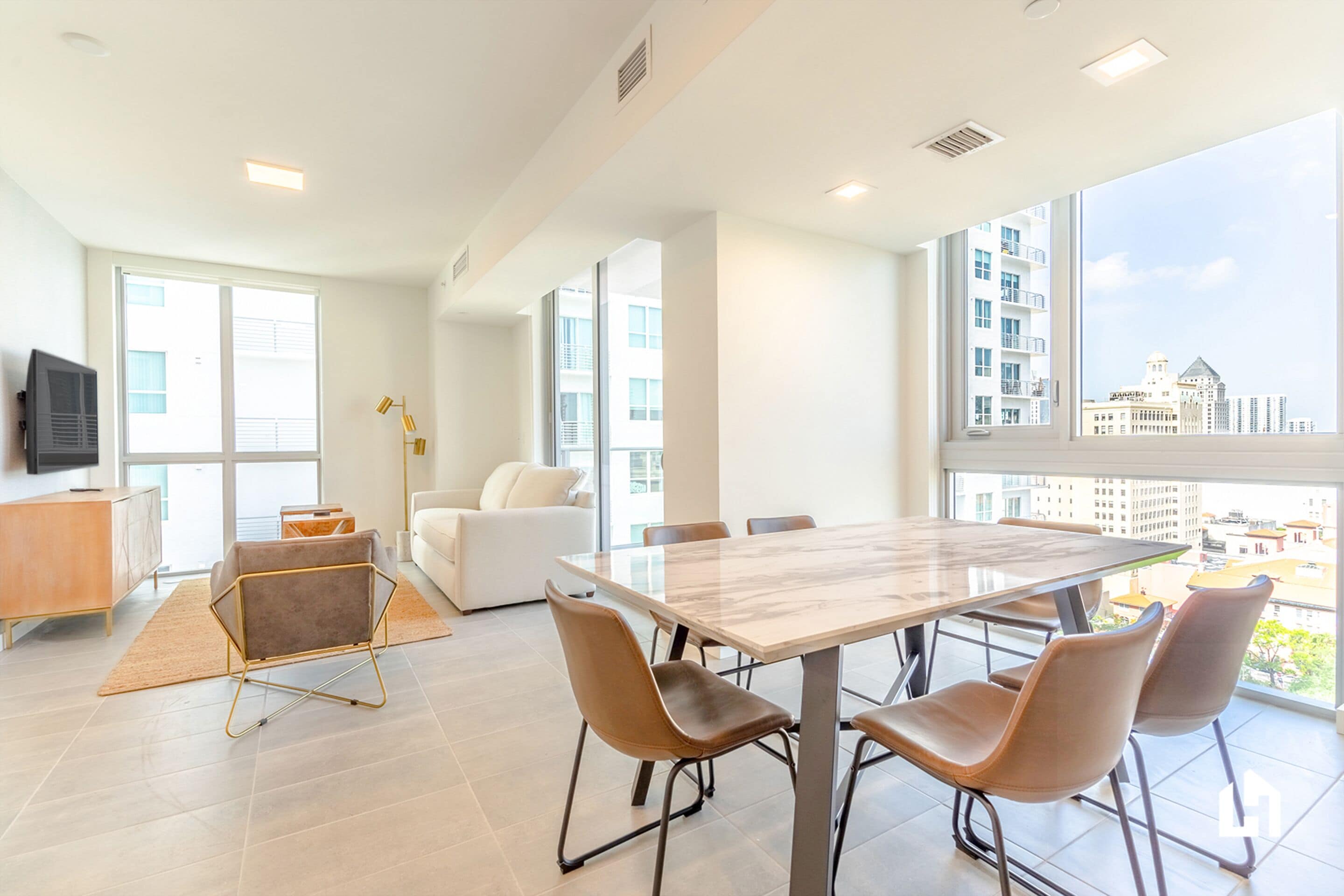 A modern living room with a large dining table, comfortable seating, a sofa, and a television.
