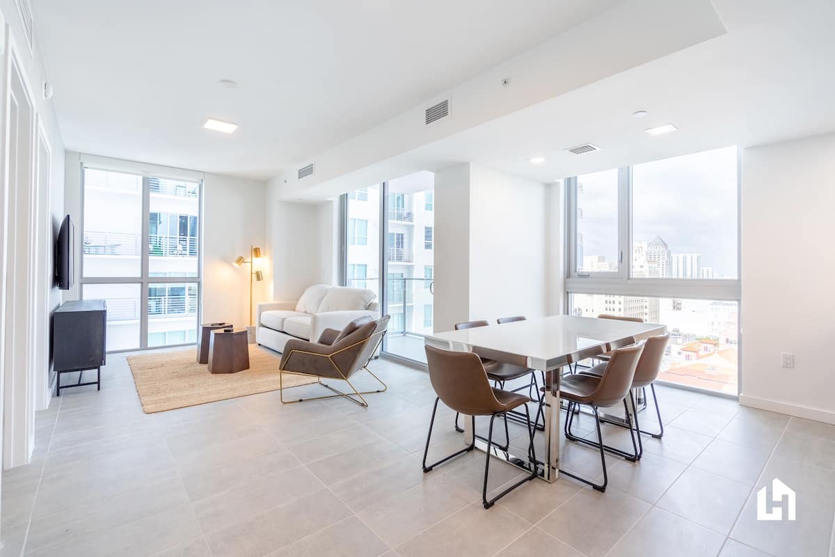 Amplia habitación con una gran mesa de comedor, asientos cómodos, un televisor de pantalla plana y ventanas amplias que ofrecen vistas de la ciudad.