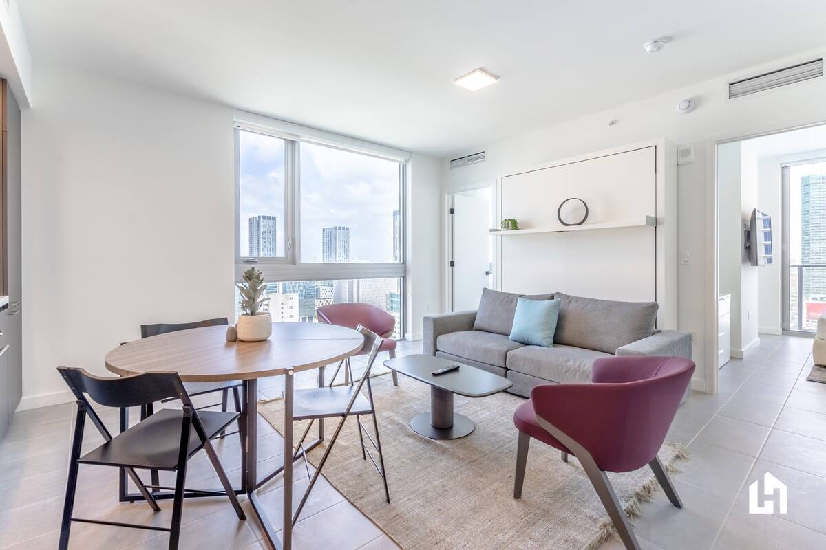 Una sala de estar moderna con comedor, ventanas amplias y vistas a la ciudad.