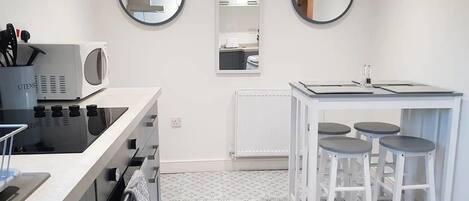 A modern kitchen with a microwave, stove, and sink. There are two round mirrors on the wall and a small bar area with stools.