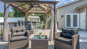 An outdoor patio with wicker furniture, a glass table, and a pergola. - Relaxing Pool & Hot Tub House near RIT Inn (West Henrietta)