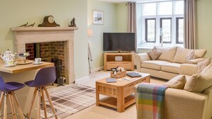 Ein Wohnzimmer mit Kamin, Fernseher, Sofa und Couchtisch.