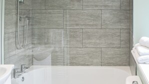 Ein Badezimmer mit Badewanne, Dusche und gefliesten Wänden.