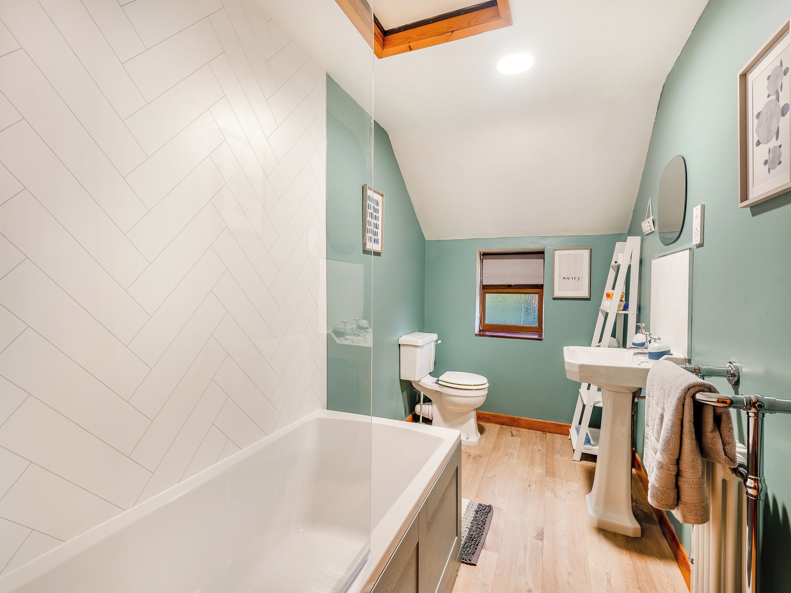 Een badkamer met een bad, toilet, wastafel en een raam.
