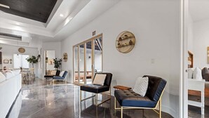 A modern living room with a polished floor, a seating area with two sofas, a coffee table, and a fireplace. - Bridgewood: Private Hot Tub + Golf + Sand Dunes (Hurricane)
