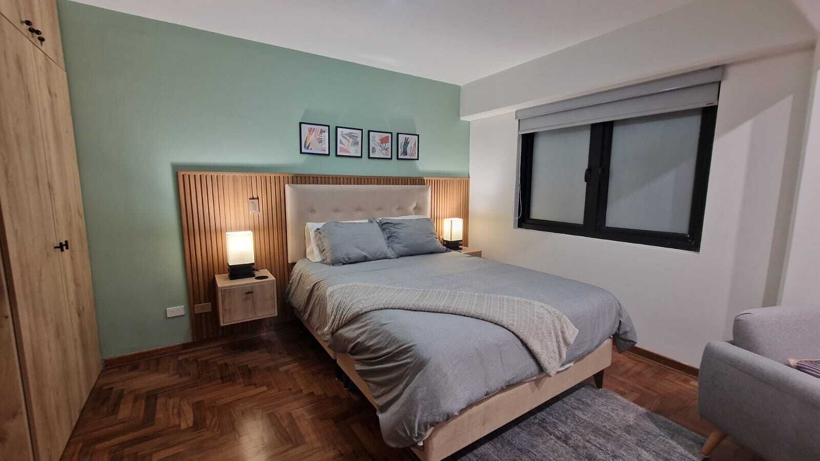 A bedroom with a bed, bedside tables, a window, and a wardrobe.