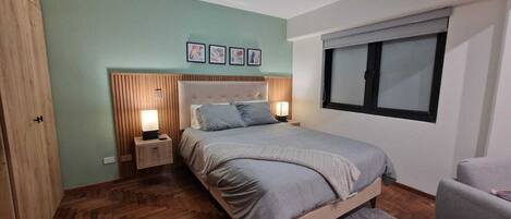 A bedroom with a bed, bedside tables, a window, and a wardrobe.