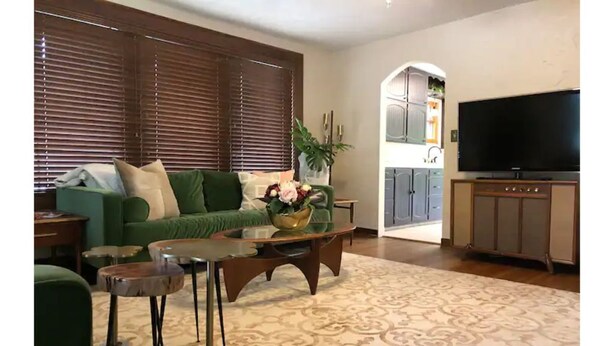 Una sala de estar con un sofá verde, una mesa de centro y un televisor.