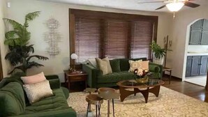 Una sala de estar con un sofá verde, una mesa de centro y un tapete estampado.