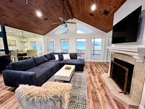 A modern living room with a sectional sofa, a fireplace, and a large TV.