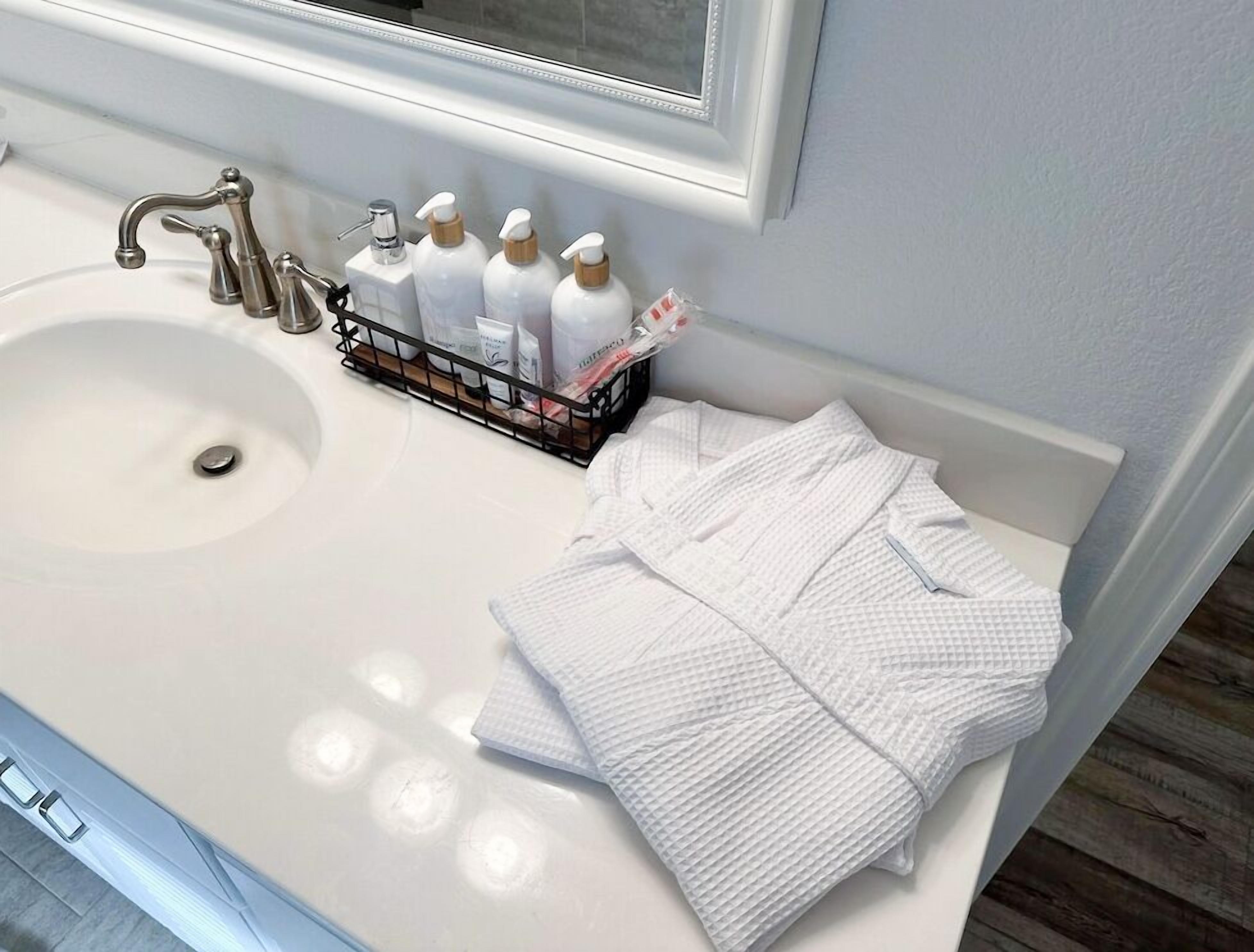 A bathroom with a white sink, a mirror above it, and a rack holding toiletries.