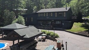 A two-story lodge with a large deck area, a pool, and a covered patio.