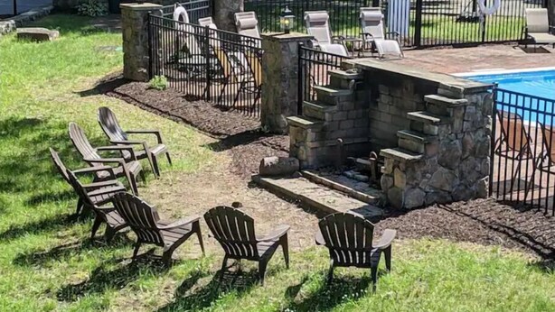 A patio area with stone steps leading to a seating area with chairs and a fire pit.