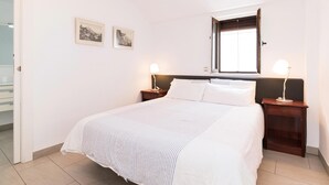 Una camera da letto con un letto, due comodini con lampade, una finestra e due quadri appesi al muro.