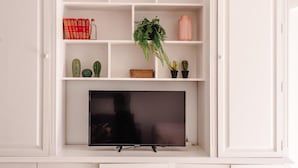 Een witte entertainmentkast met een flatscreen televisie, boeken en diverse decoratieve objecten.