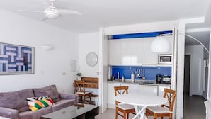 Een moderne woonkamer met een bank, salontafel, en een eethoek met stoelen en een tafel.