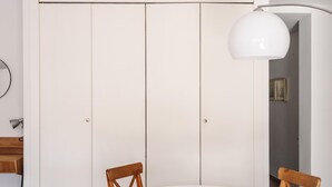 Een kamer met een witte kast, een ronde tafel en twee houten stoelen.