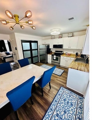 A modern kitchen with white cabinets, a central island, and a dining area with blue chairs. - Escape to Comfort in Lexington/Hamburg: Stylish 3BR/2.5BA Home (Lexington)