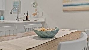 Eine moderne Küche mit weißen Schränken, einer weißen Arbeitsplatte und einer blauen Keramikschüssel auf einem Holztisch.