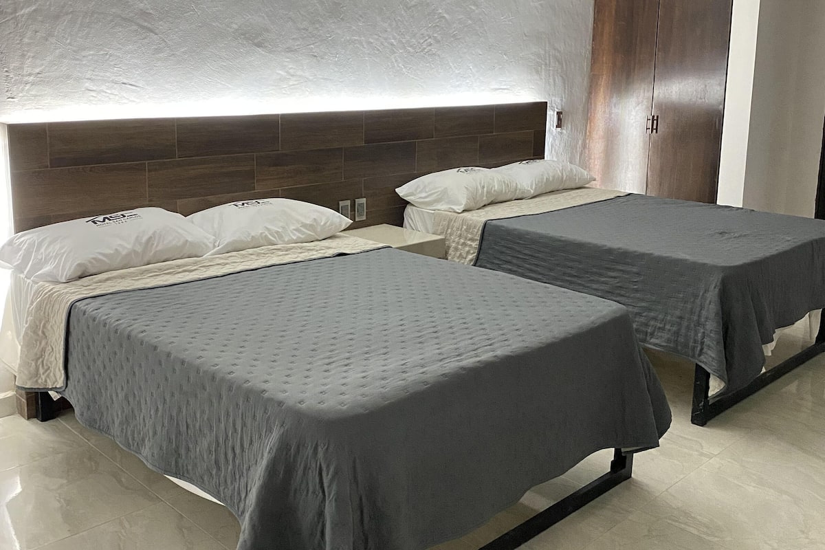 A hotel room with two beds, a wooden headboard, and a wardrobe.