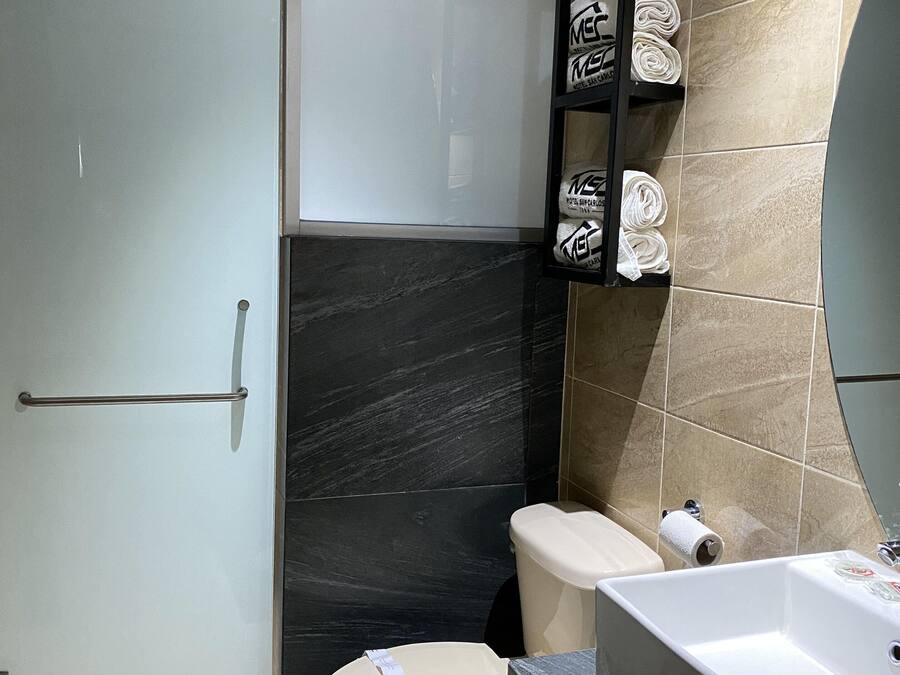 Un baño moderno con inodoro, lavamanos y cabina de ducha de vidrio.