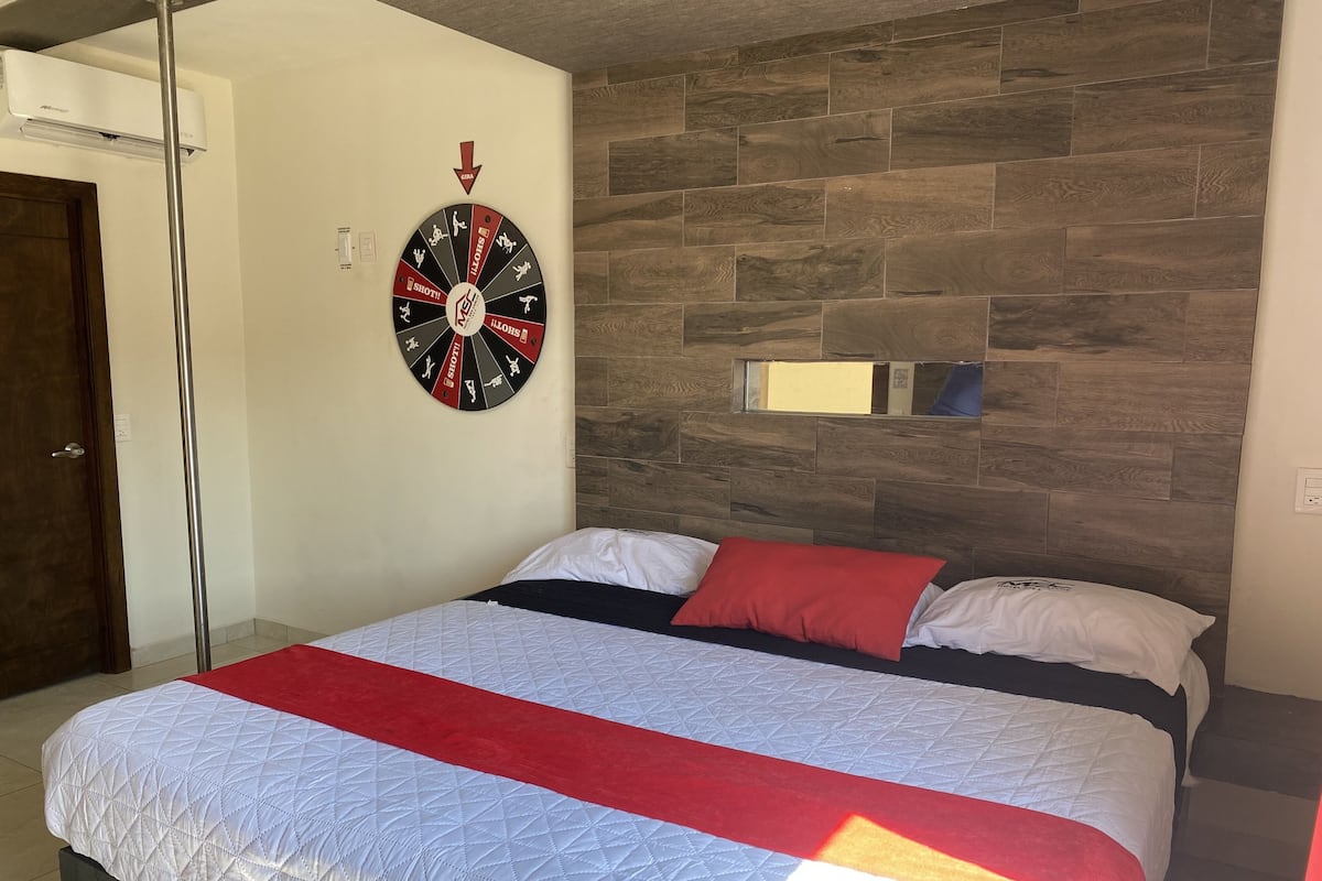 A bedroom with a bed, a wall clock, and a wooden headboard.