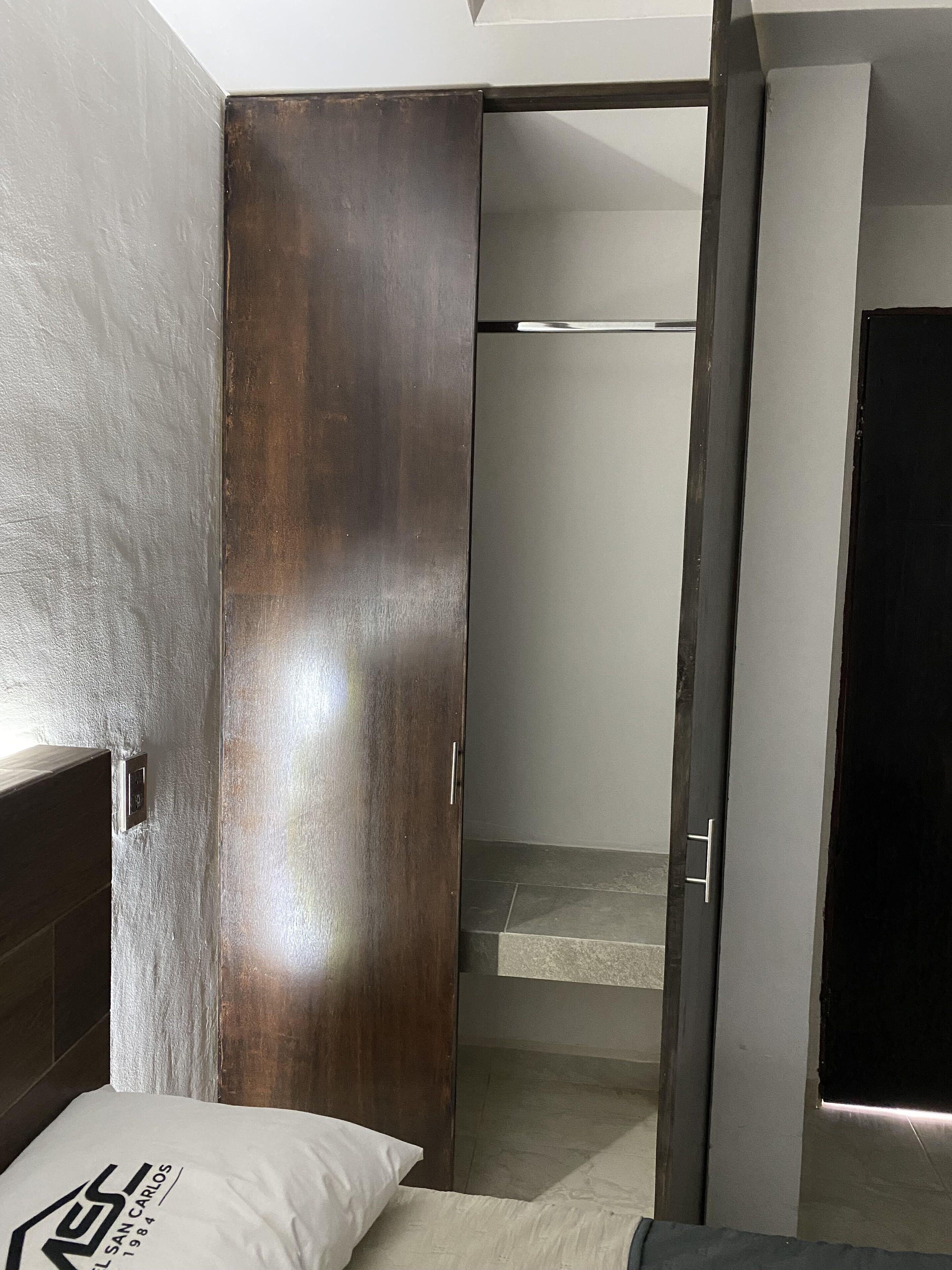 Una habitación con una cama, un armario de madera y una puerta corredera que da a un baño.