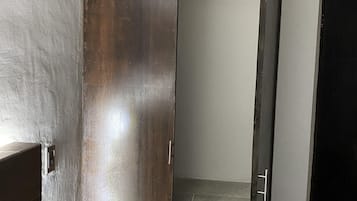 Una habitación con una cama, un armario de madera y una puerta corredera que da a un baño.