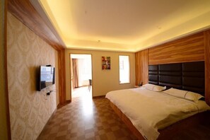 A bedroom with a large bed, a flat-screen TV mounted on the wall, and a door leading to another room. - Nuoman Holiday Hotel (Xiantao)