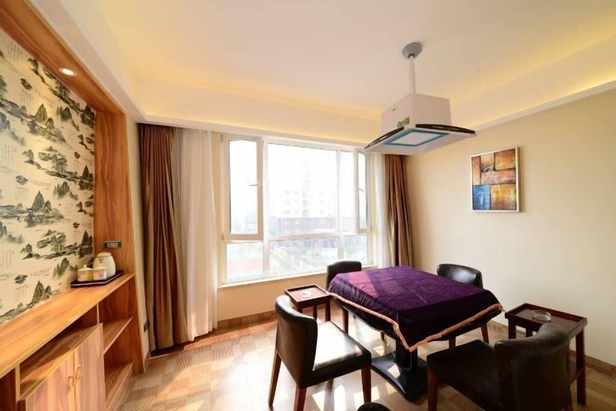 Habitación de hotel con cama, escritorio, silla, mesita y ventana con cortinas.