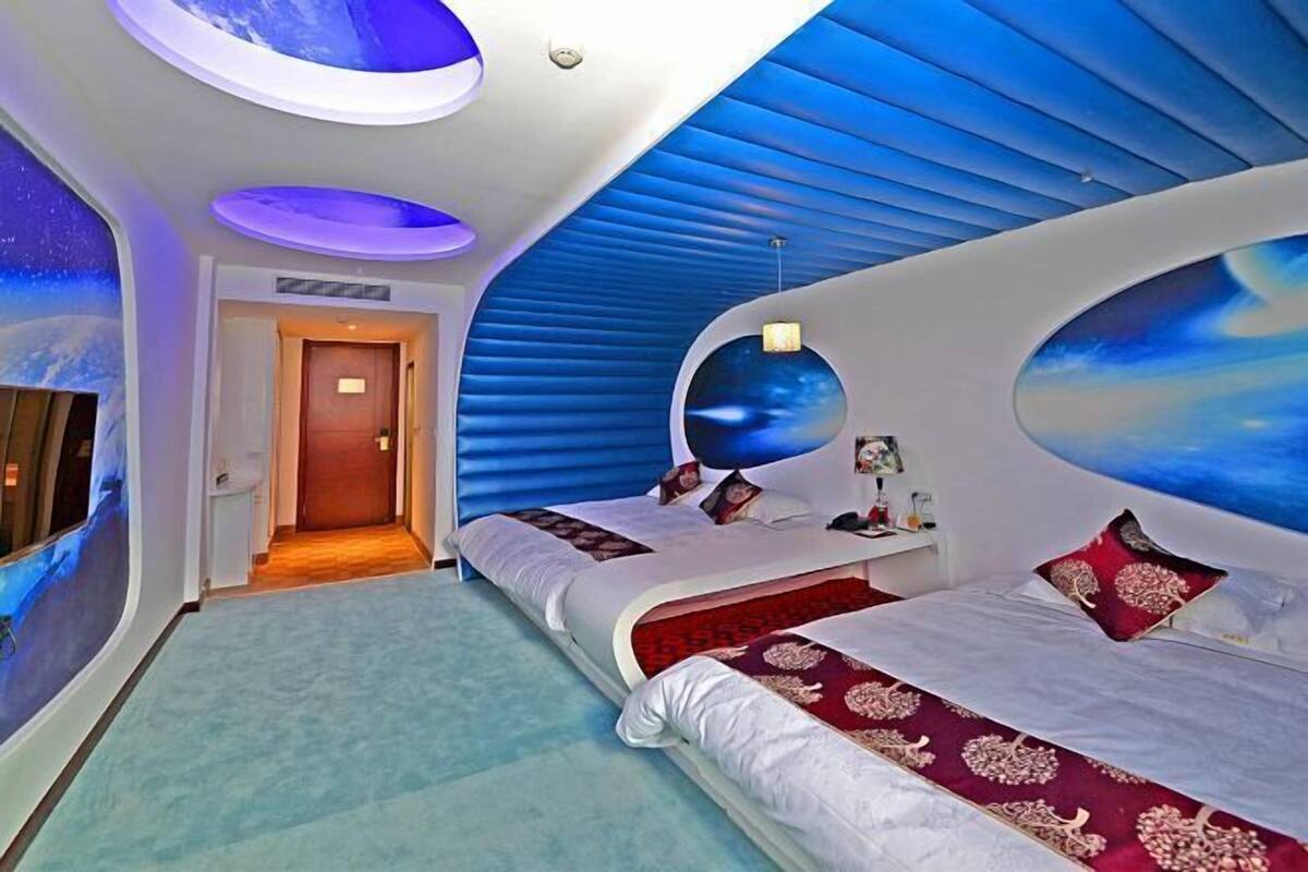 Un dormitorio moderno con paredes curvas, un tragaluz circular y una cama con colcha de diseño rojo y blanco.