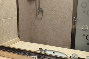 A bathroom with a shower, a sink, and a mirror. - Nuoman Holiday Hotel (Xiantao)