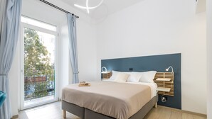Un dormitorio con cama, mesita de noche, cortinas en la ventana y vistas al exterior.