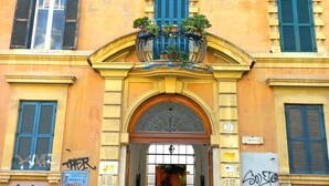 Un edificio con fachada amarilla, contraventanas azules y una entrada central con un arco decorativo.