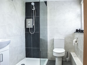 Een moderne badkamer met een douchecabine van glas, een toilet en een wastafel.