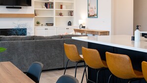 Une cuisine moderne avec un coin repas, comprenant une table en bois, des tabourets de bar et un îlot central intégré.
