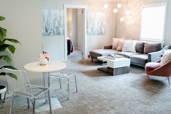 Ein modernes Wohnzimmer mit einer Couch, einem Couchtisch und transparenten Glasstühlen.