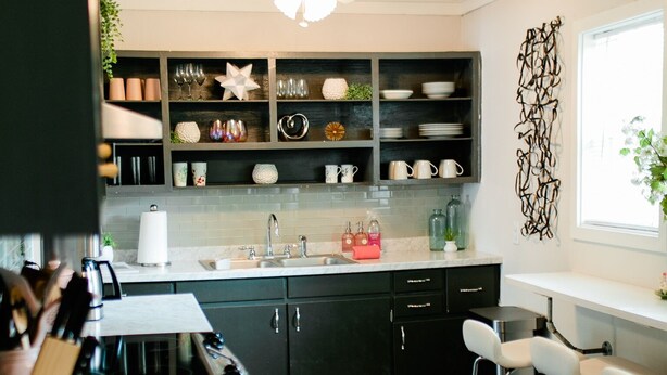A modern kitchen with dark cabinets, a white countertop, and a built-in bar area with stools. - Virginia Modern Luxe (Springfield)